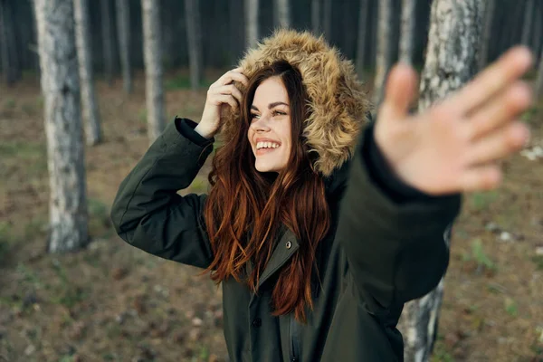 Veselá žena v bundě v lese gesta s rukama — Stock fotografie