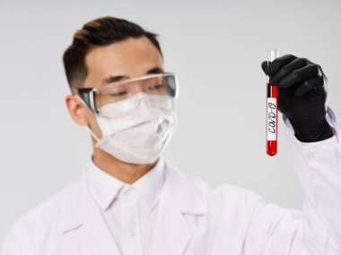 Kan tahlili laboratuvar koruyucu maskeli erkek doktor test tüpü.