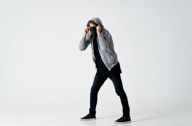 Gri kazaklı erkek hacker yüzünde siyah bir maske çalıyor.