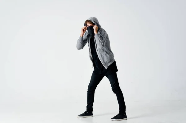 Male hacker in a gray sweater stealing black mask on his face — Stock Photo, Image