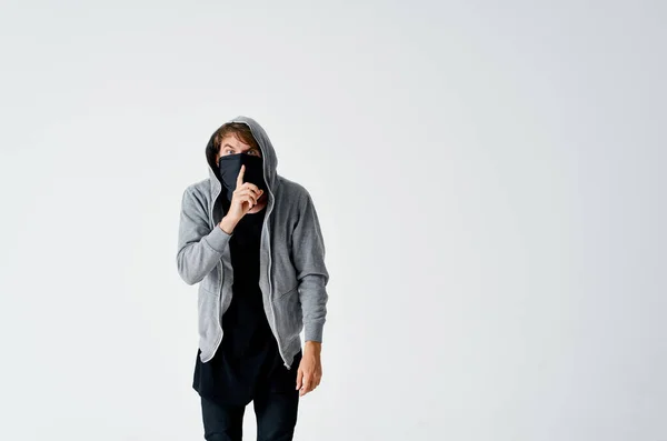 Mannelijke hacker in een zwart masker en in een kap op een lichte achtergrond diefstal — Stockfoto