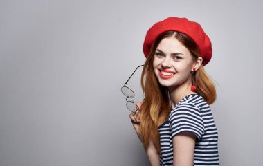 Kırmızı şapkalı ve çizgili tişört gözlüklü kadın yüz portresi üzerinde.