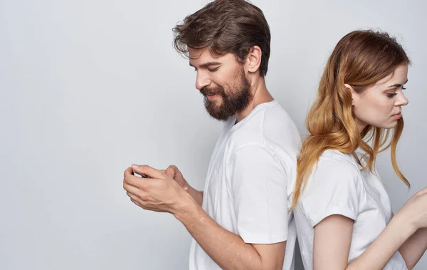 携帯電話を手にした白いTシャツを着た若いカップルがインターネットライフスタイルを伝え — ストック写真
