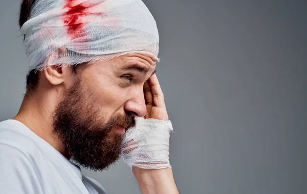 Ένας άντρας με μια επίδεσμη στο κεφάλι χειρουργική επέμβαση ανάνηψης του αίματος μοντέλο γάζα στο χέρι του — Φωτογραφία Αρχείου