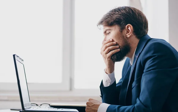 Hombre de negocios en su escritorio en un traje delante de la oficina de comunicación portátil profesional — Foto de Stock