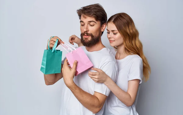 Hombre y mujer enamorados con bolsas de regalo sobre fondo gris vista recortada —  Fotos de Stock