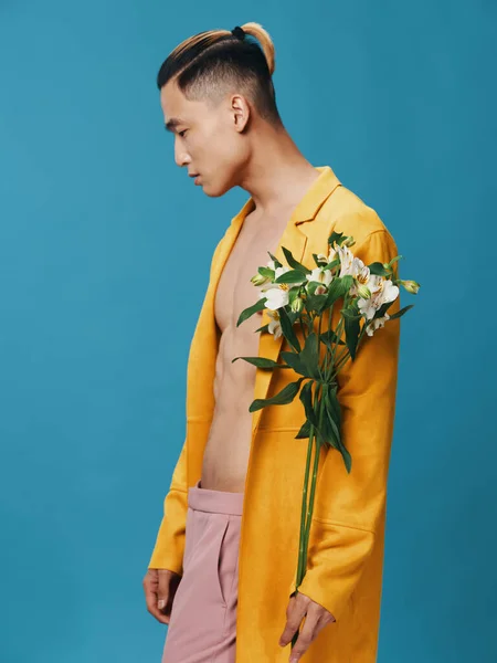 Homem romântico no casaco amarelo torso nu e buquê de flores vista cortada fundo azul — Fotografia de Stock
