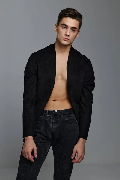 A gentleman in an unbuttoned jacket on a naked torso and in trousers on a gray background — Stock Photo, Image