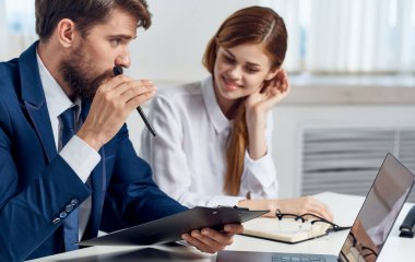 İşyerindeki çalışanlar laptopla iletişim belgeleri hazırlıyorlar.