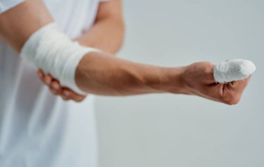 Kolu yaralı bir adam hastaya bandaj yapıyor.