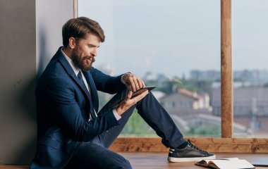 Ofisteki iş adamı elinde tabletle pencerenin yanında profesyonel biri.