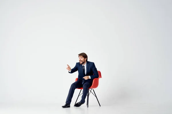 Homme d'affaires assis sur des chaises rouges à l'intérieur et des gestes avec ses mains — Photo