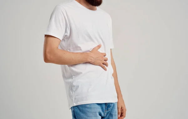 Cara em uma camiseta e jeans toca suas mãos perto do abdômen dor problemas de estômago apendicite — Fotografia de Stock