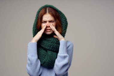 Kafasına fular ören bir kadın. Sağlık sorunları. Burnu akan mavi süveter.