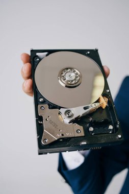 Hard disk, gri bir arka planda bir adamın elinde parçalara ayrıldı.