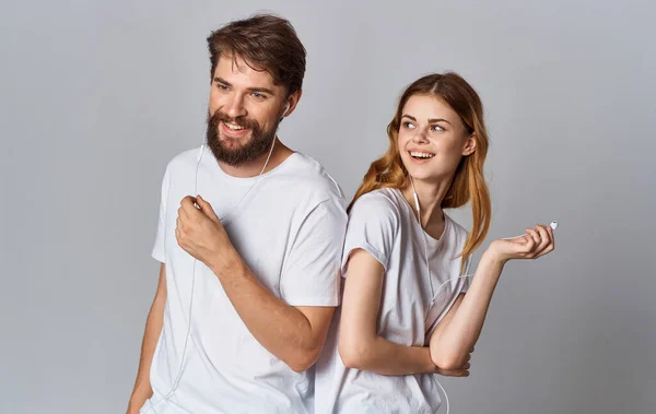 Glad man och kvinna i hörlurar på grå bakgrund titta och stå med ryggen mot varandra — Stockfoto