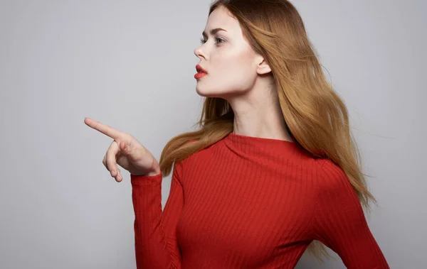 Retrato de uma mulher bonita em uma camisa vermelha em um fundo cinza gestos com as mãos Copiar Espaço — Fotografia de Stock