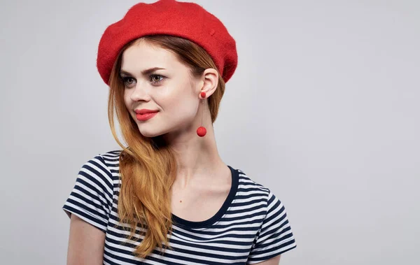 Mujer alegre con sombrero rojo y camiseta a rayas haciendo gestos con las manos y sonriendo —  Fotos de Stock