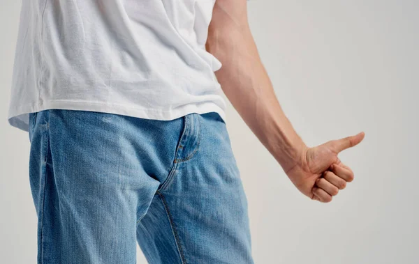Ein Mann in Jeans und T-Shirt zeigt einen Daumen unter der Gürtellinie — Stockfoto