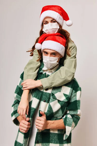 Щасливі чоловіки і жінки в новорічних капелюхах і в медичній масці. — стокове фото