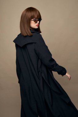 Çekici model siyah ceket, parlak makyaj izole bir arkaplanda duruyor. 