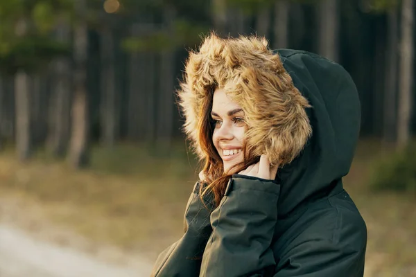 Glimlachende vrouw in capuchon jas kijkt aan de zijkant frisse lucht vreugde van reizen — Stockfoto