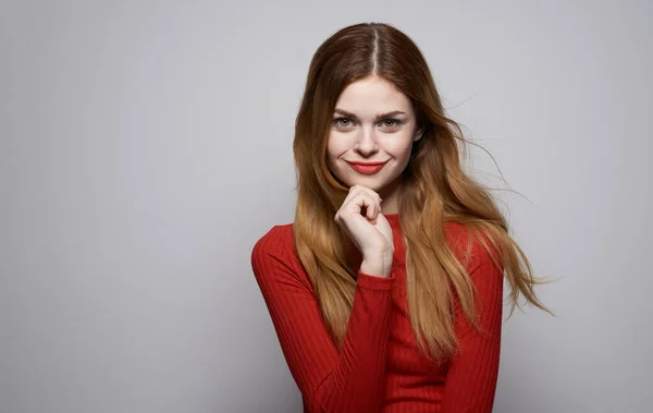 Mulher emocional gesticulando com as mãos em um fundo leve vermelho suéter modelo maquiagem — Fotografia de Stock