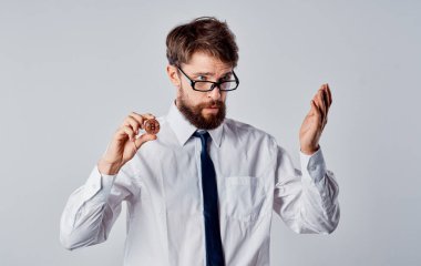 Elinde bozuk para olan bir adam arka planda bitcoin kripto para görüntüsünü kırpmış.