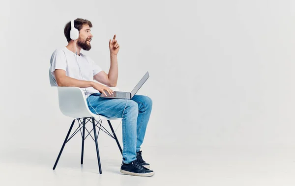 Homem sentado na cadeira na frente do laptop em fones de ouvido tecnologia de comunicação isolado fundo — Fotografia de Stock