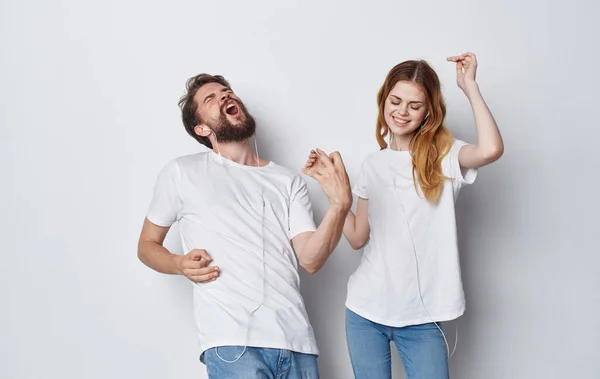 Happy friends in headphones listens to music and dances on a light background — Stock Photo, Image