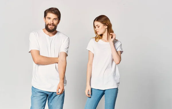 Un uomo e una donna in jeans e una t-shirt su uno sfondo chiaro gesticolando con le mani ritratto amici famiglia — Foto Stock