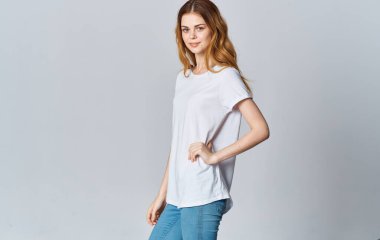 Beyaz tişörtlü güzel bir kadın ve gri arka planda kot pantolon. Boşluğu kopyala.