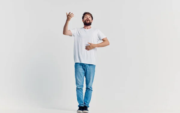 Uomo emotivo in t-shirt bianca e jeans gesticolando con le mani abiti casual sfondo isolato — Foto Stock
