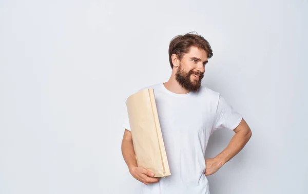 Homem alegre em uma camiseta branca com um saco de artesanato nas mãos de uma viagem de compras Studio — Fotografia de Stock