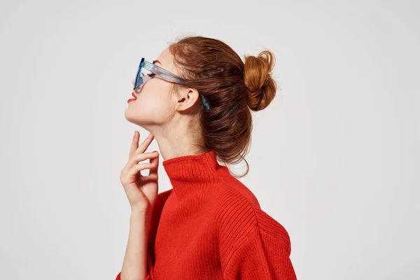 Kırmızı süveterli güzel bir kadın mavi gözlüklü ve açık arkaplan — Stok fotoğraf
