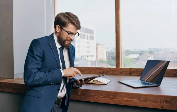 Um homem em um terno com um tablet nas mãos de uma tecnologia de laptop de escritório Profissional — Fotografia de Stock
