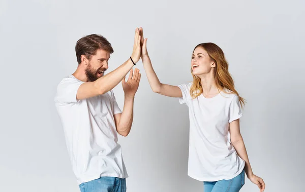 Hombre emocional en una camiseta y una mujer en pantalones vaqueros sobre un fondo claro ropa estilo de moda — Foto de Stock