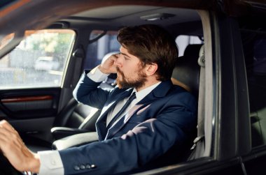 Takım elbiseli bir adam araba kullanıyor. Başarılı bir memur telefonda konuşuyor.