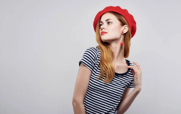 Модель в красной шляпе и в полосатой футболке на светлом фоне эмоций портрет обрезанный вид — стоковое фото