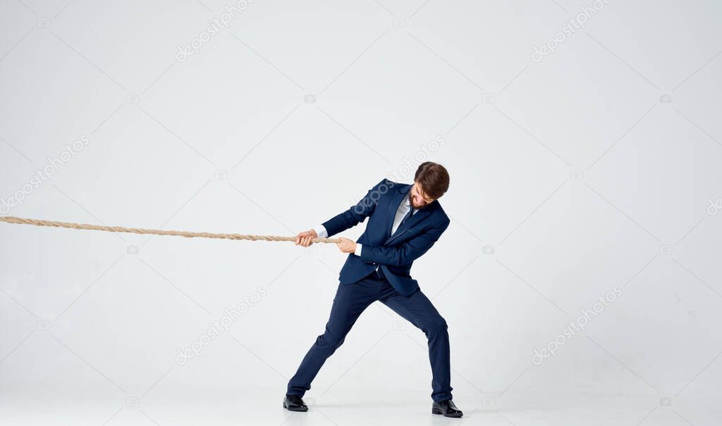 business man in a suit pulls a rope on a light background