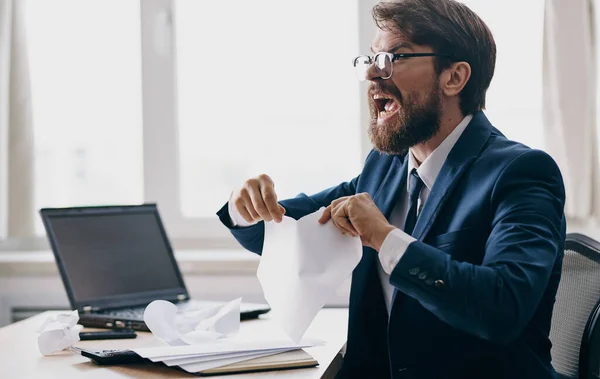 Impulsive man with white sheets of paper in hands emotions office business finance laptop