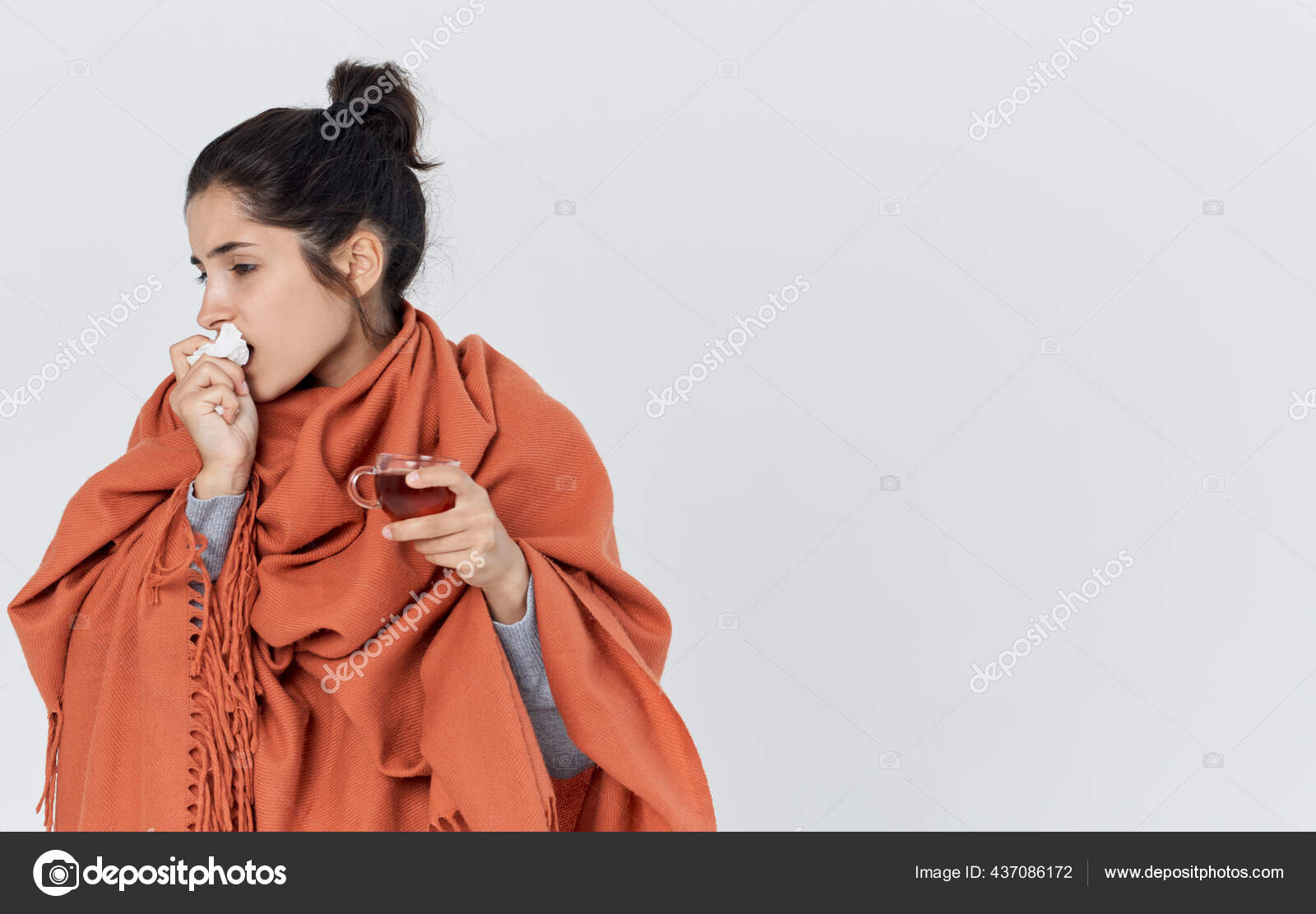Woman with orange on her shoulders wipes her nose with a napkin