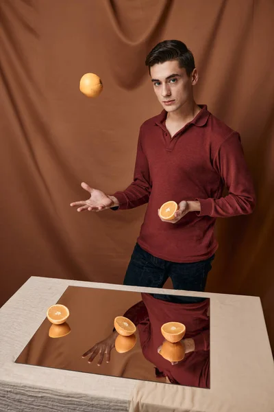 En man i röd skjorta med apelsiner nära bordet med spegel — Stockfoto