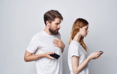 Beyaz tişörtlü kadın ve erkek ellerinde telefonla romantik iletişim teknolojisi.