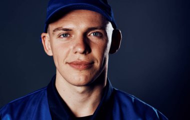 Mavi üniformalı bir adam teslimat servisinde çalışıyor.