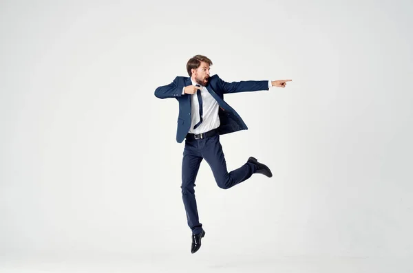 Energetico uomo d'affari in un abito blu salta su uno sfondo leggero successo gioia emozioni — Foto Stock