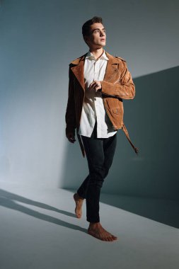 Gri arka planda kahverengi ceketli şık bir adam ve duvarda gölgeler şeklinde bir eğim.