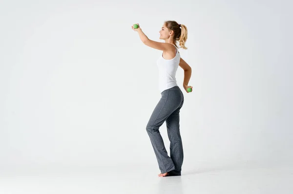 Mujer haciendo ejercicios en ropa deportiva sobre un fondo claro en interiores —  Fotos de Stock