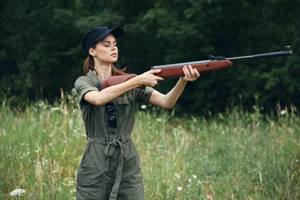 Mujer al aire libre sosteniendo un arma en frente de él la caza de vistas laterales hojas verdes — Foto de Stock