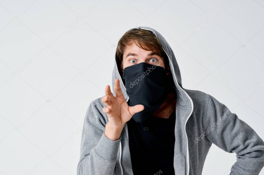 thief male hacker in a black mask and in a hood on a light background theft